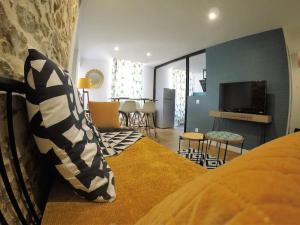 a bedroom with a couch and a living room with a tv at L'Ecrin de Pauline in Dinan