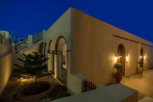 a building with a tree in a courtyard at night at AENAON ESTATE 1896 by K&K in Pirgos