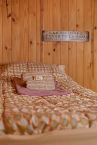 ein Bett mit einer Decke und einem Schild an der Wand in der Unterkunft Nómada in San Martín de los Andes