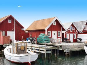 ein Boot an einem Dock mit roten Häusern angedockt ist in der Unterkunft Holiday home KUNGSHAMN III in Kungshamn