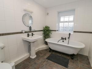 een badkamer met een bad, een wastafel en een spiegel bij Bodrual Cottage in Caernarfon +39 foto's