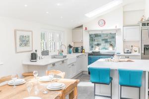 a kitchen with white cabinets and a table with blue chairs at Thwaite Cottage Coniston in Coniston