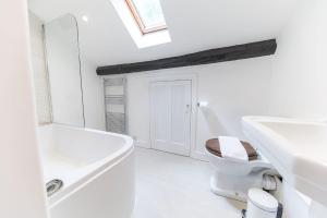 a white bathroom with a toilet and a sink at Thwaite Cottage Coniston in Coniston