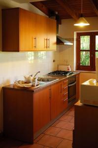 a kitchen with wooden cabinets and a sink and a stove at Vale do Guizo: Casa Poente on the contryside, close by the sea. in Aljezur