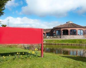 a red sign in the grass in front of a building at Leonardo Hotel and Conference Venue Hinckley Island in Hinckley