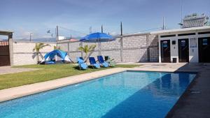 a swimming pool with two blue chairs and an umbrella at Maktub TlayaGlamping in Tlayacapan