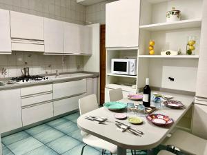 una cocina con armarios blancos y una mesa y sillas blancas. en Sorrento Home Pool family BIG appartament in Sorrento center, en Sorrento