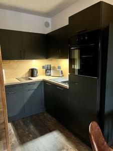 eine Küche mit schwarzen Schränken und einem schwarzen Kühlschrank in der Unterkunft Location studio jardin/terrasse in Gréolières
