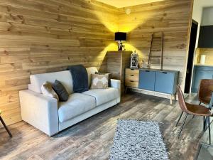 ein Wohnzimmer mit einem weißen Sofa und einer Holzwand in der Unterkunft Location studio jardin/terrasse in Gréolières