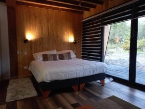 a bedroom with a bed and a large window at Cabañas Los Volcanes Ensenada Puerto Varas in La Ensenada