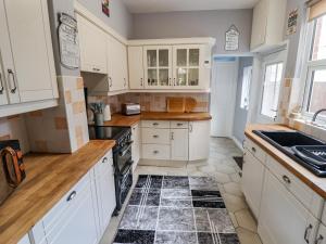 een keuken met witte kasten en een zwart-witte tegelvloer bij Coastguard Cottages in Hull