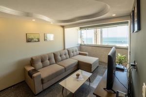 sala de estar con sofá y TV en Modern apartment with Ocean View - 500m from Beach, en Fortaleza