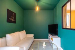 uma sala de estar com um sofá branco e uma televisão em Appartement Cosy Art Déco/ Proche centre-ville em Nantes