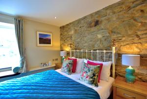 a bedroom with a bed and a stone wall at Bryn Tyrch Rooms in Capel-Curig