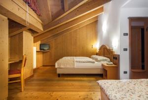 a bedroom with two beds and a tv on a wall at Hotel Pedranzini in Santa Caterina Valfurva