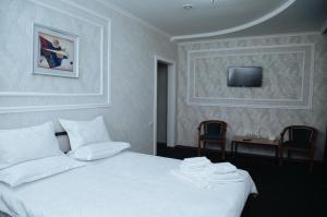 um quarto com uma cama branca e uma televisão na parede em SELFIE + em Semei