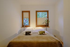 a bedroom with a large bed with two windows at Waldvilla BERGSEE in Bodensdorf