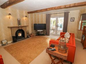 a living room with a red couch and a fireplace at Clerk Beck Cottage in Ulverston