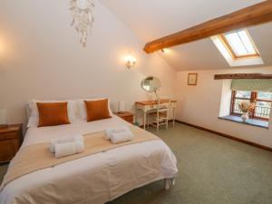 a bedroom with a large bed and a desk at Clerk Beck Cottage in Ulverston