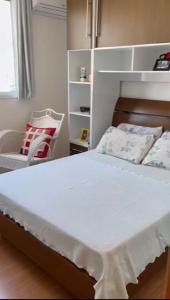 1 dormitorio con 1 cama blanca y 1 silla en Jardim da Costa perto da Praia e UFPB, en João Pessoa