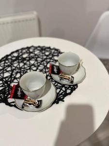 a white table with two tea cups on a plate at Apartment Comfort in Bartoszyce