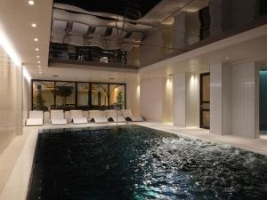 a pool in the middle of a building with white chairs at The Other House South Kensington in London