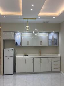 uma cozinha com armários brancos e um frigorífico branco em شالية الجوهرة em Taif