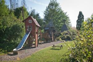 a playground with a slide and a bench in a park at Sleep Space 25 - Green Tiny Village Harz in Osterode