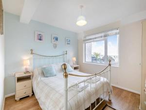a bedroom with a white bed and a window at Sandcastles - Mount Brioni in Downderry