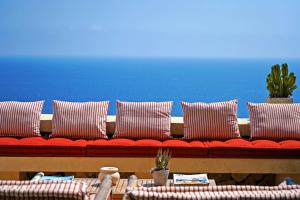 a red couch with pillows and a blue wall at Le Capase Resort Salento in Santa Cesarea Terme