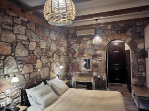 a bedroom with a stone wall with a bed and a mirror at Ataviros Hotel in Émbonas +75 photos