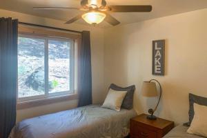 a bedroom with a ceiling fan and a window at Rustic Retreat with Deck Steps From Lake Almanor! in Lake Almanor
