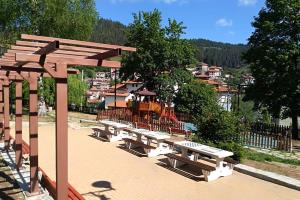 a group of picnic tables in a park with a playground at Къща за гости Малините in Chepelare