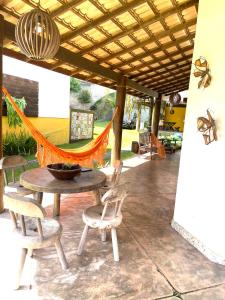 a patio with a table and chairs and a hammock at Casa da Rô !!! Melhor casa frente ao mar de Ubu !!! in Anchieta