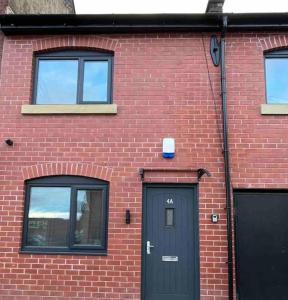 a brick building with a black door and two windows at New Build Cosy Duplex Modern Apartment Greater Manchester in Stockport