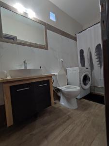 a bathroom with a toilet and a sink and a washing machine at Aithra Studio in Tripoli