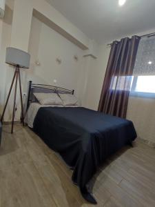 a bedroom with a bed with a black blanket and a window at Aithra Studio in Tripolis