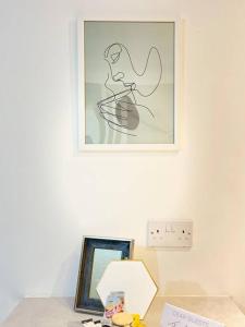 a picture on a wall above a table with a picture at New Build Cosy Duplex Modern Apartment Greater Manchester in Stockport