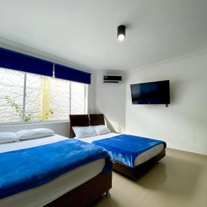 a bedroom with two beds and a flat screen tv at CASA PALMA CARTAGENA in Cartagena de Indias