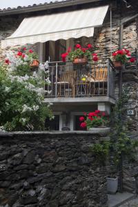un balcone con sedie e fiori su un muro di pietra di Rustico Giorgia a Mergozzo