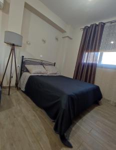 a bedroom with a bed with a black blanket and a window at Aithra Studio in Tripoli