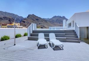 two chairs sitting on a deck with mountains in the background at Alse Homes Adeje Mountain and Seaview in Adeje