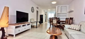 uma sala de estar com um sofá e uma televisão num armário em Large apartment with sea view em Bat Yam