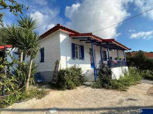 a white house with blue windows and a palm tree at Villa Vrachos - uriges Steinhaus - in Vráchos