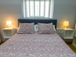 een slaapkamer met een bed met een paars dekbed en 2 lampen bij Apartamento Plaza Viuda in Cádiz
