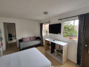 Un dormitorio con una cama, un televisor y un sofá. en Mountain View, en Curitiba