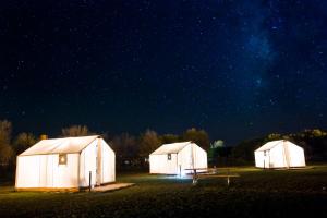 a couple of white buildings in a field at night at El Cosmico in Marfa