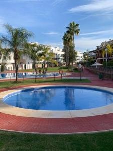 uma piscina num parque com palmeiras e edifícios em CT 209 - Navigolf Penthouse - La Cala de Mijas em La Cala de Mijas