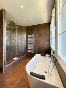 a large bathroom with a tub and a shower at Le Grand Hôtel Le Touquet-Paris-Plage in Le Touquet-Paris-Plage