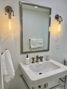 a white bathroom with a sink and a mirror at Oceanfront Fully Remodeled 2BR 2BA, Pool, Hot Tub, Gated Parking in Solana Beach